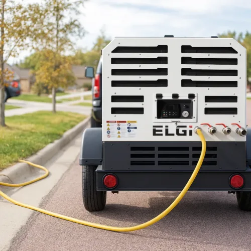 Compresseur d’air mobile utilisé pour la purge de systèmes d’irrigation résidentiels en automne, avec tuyau connecté sur une pelouse de quartier. Équipement d’hivernisation, entretien extérieur, compresseur portatif pour irrigation.